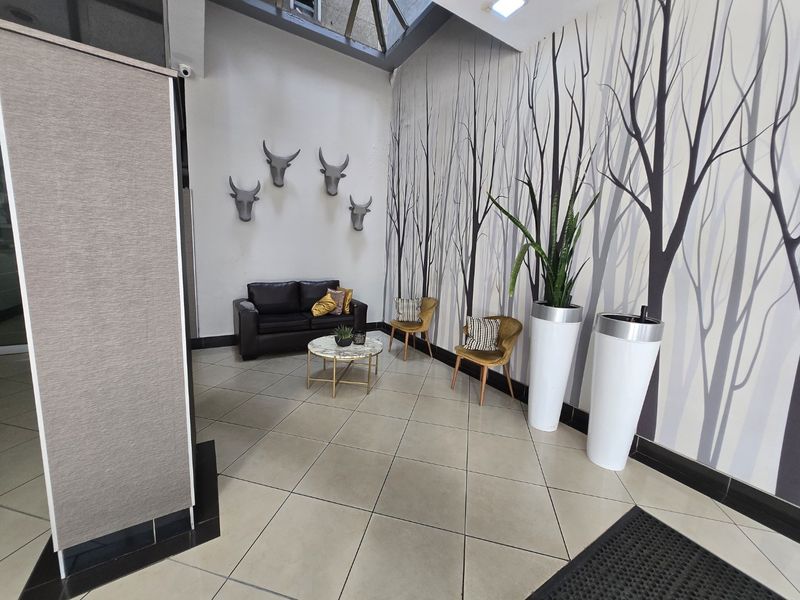 A bright entrance foyer featuring tiled flooring, a large skylight, and decorative wall finishes, creating a welcoming and modern reception area.