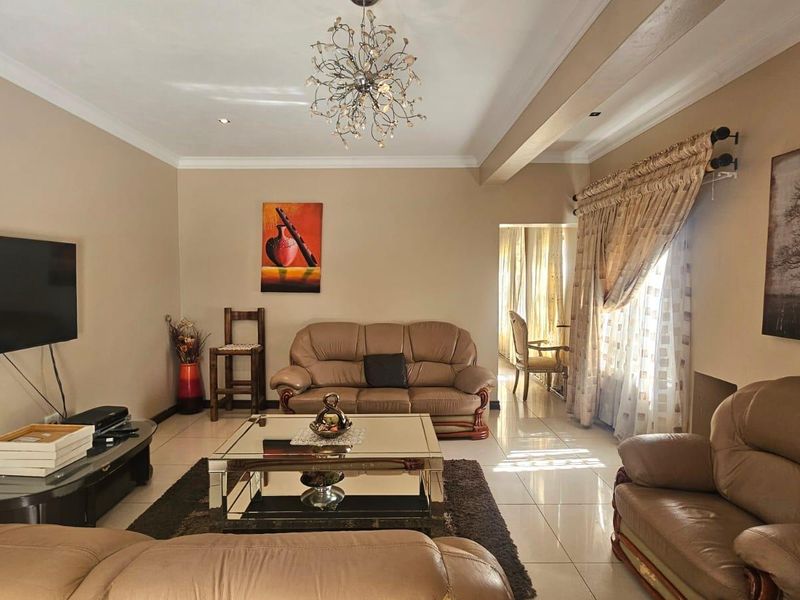 A well-maintained living room featuring tiled flooring, coved cornicing, and a decorative chandelier, providing a comfortable and inviting space.