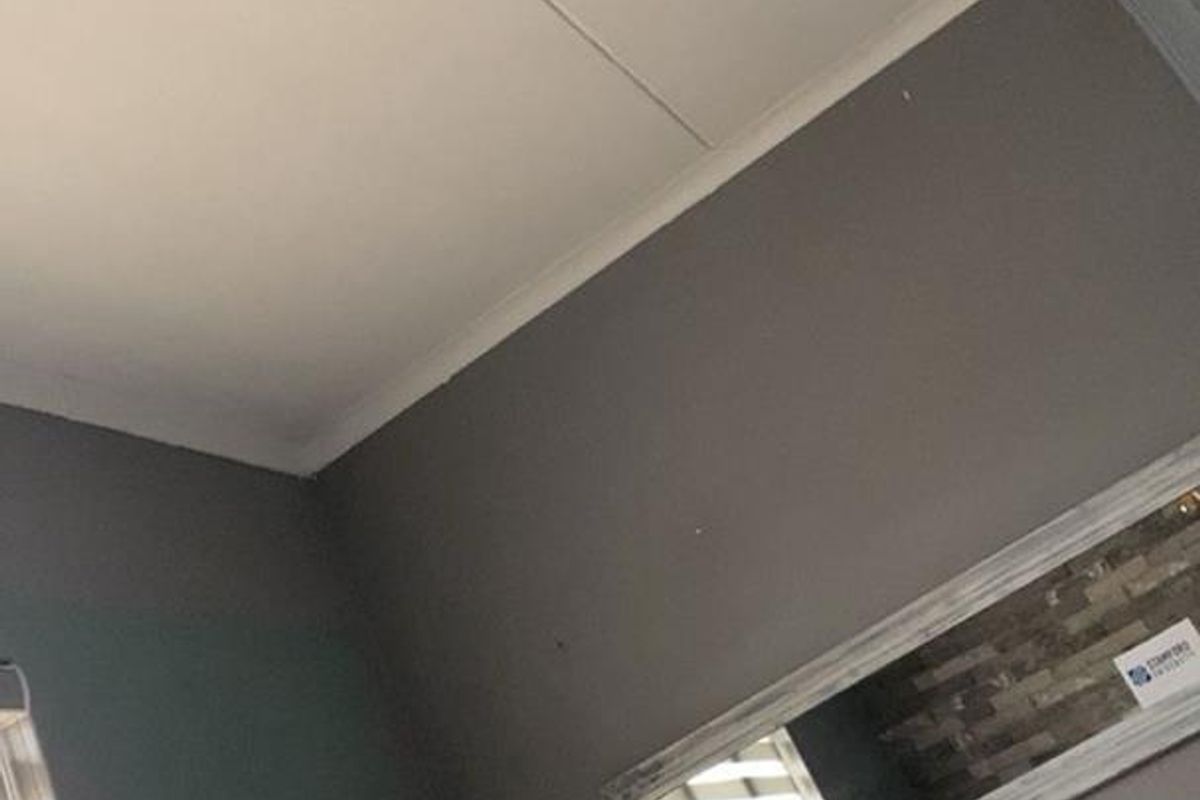 A bedroom interior featuring grey walls with decorative accents, a floating shelf, and modern pendant lighting.
