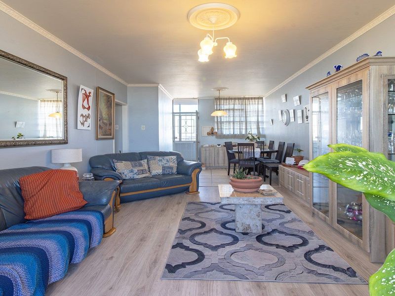 Spacious open-plan living and dining area featuring light-toned laminate flooring, decorative ceiling roses, and coving throughout the combined space.