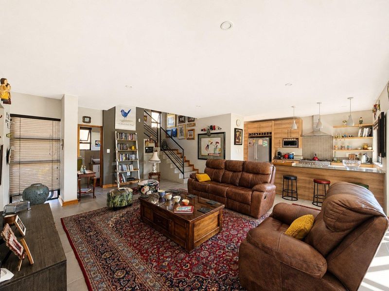 Spacious open-plan living area featuring a modern kitchen with wood-finish cabinetry, a central island, and an integrated staircase leading to the upper level.