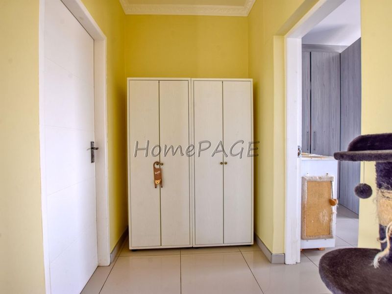 A bright hallway featuring tiled flooring, crown molding, and access to adjacent rooms.