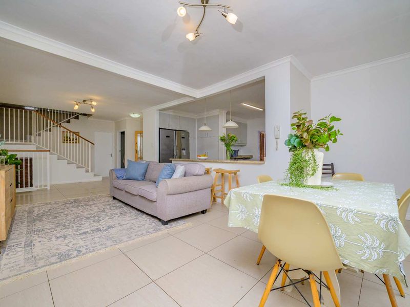 Open plan living and dining area featuring tiled floors, a staircase with balustrade, and a breakfast bar connecting to the kitchen.