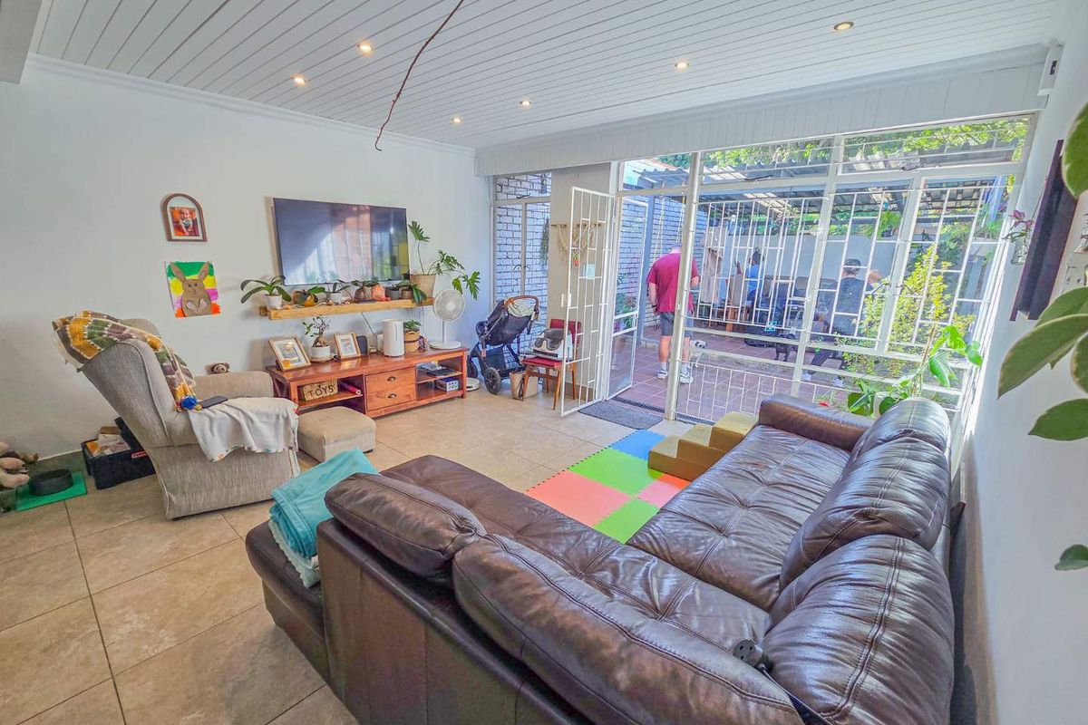 A bright living room featuring tiled floors, recessed lighting, and large glass doors providing direct access to the outdoor patio area.