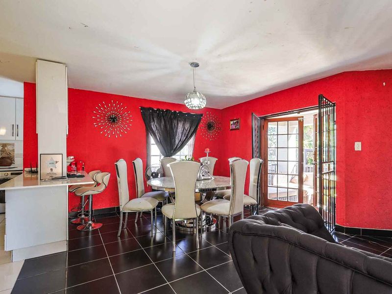 Open-plan living and dining area featuring tiled floors, kitchen cabinetry, and direct access to the patio through French doors.