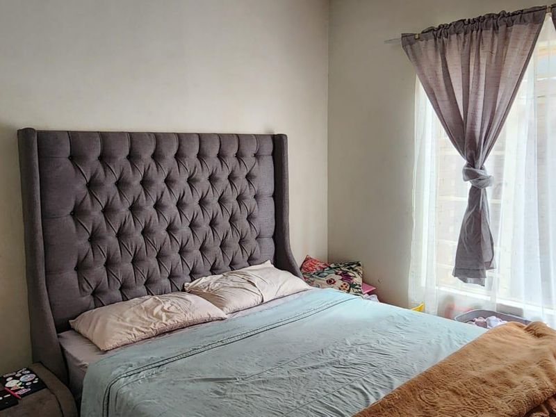 A bedroom featuring a window with installed curtain rods and neutral wall finishes.