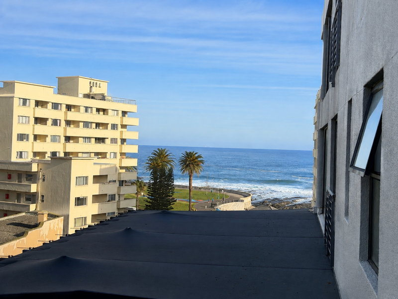 A scenic coastal view overlooking the ocean, promenade, and surrounding apartment buildings from an elevated vantage point.