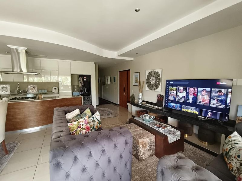 Modern open-plan living area featuring a sleek kitchen with built-in cabinetry, gas hob, and stainless steel extractor, flowing into a comfortable lounge space.