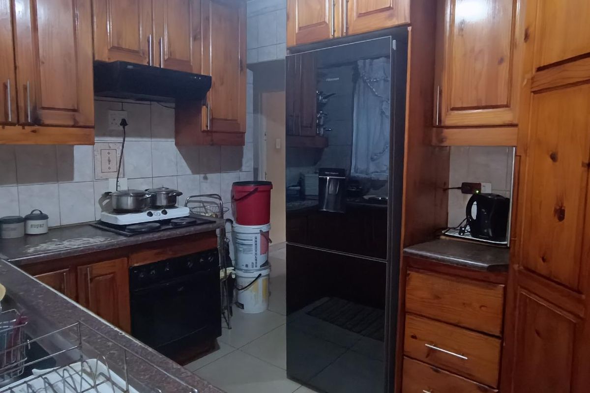 A functional kitchen featuring solid wood cabinetry, a built-in oven with extractor fan, and tiled countertops.