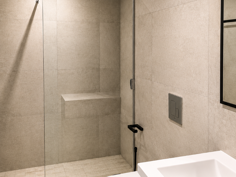 Modern bathroom featuring a walk-in shower with a rain shower head, built-in bench, wall-mounted toilet, and a sleek vanity basin.