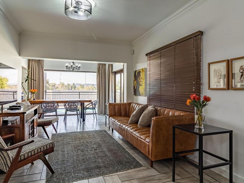 Spacious open-plan living area featuring tiled flooring, crown molding, and large sliding glass doors that provide seamless access to the outdoor patio space.