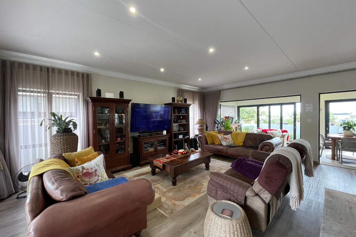 Spacious living room featuring recessed downlighting, laminate flooring, and large sliding glass doors providing access to the outdoor area.