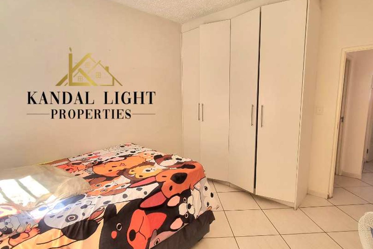 A bedroom featuring built-in white wardrobes and tiled flooring, providing functional storage space within the apartment.