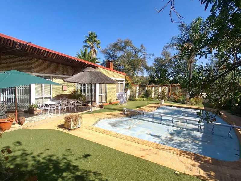 Outdoor pool area featuring a swimming pool with cover, brick paving, artificial lawn, and a covered patio space.