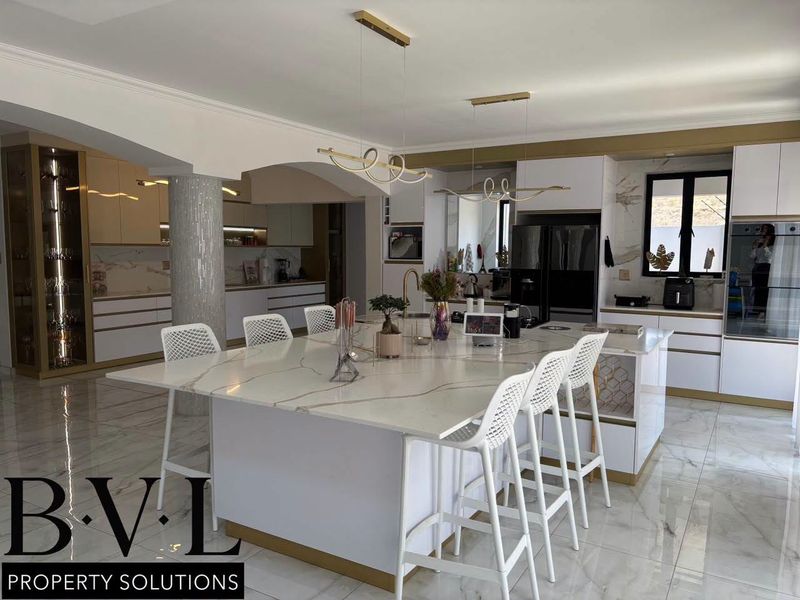Modern, high-end kitchen featuring a large marble-topped island, integrated cabinetry, premium finishes, and elegant pendant lighting in an open-plan layout.