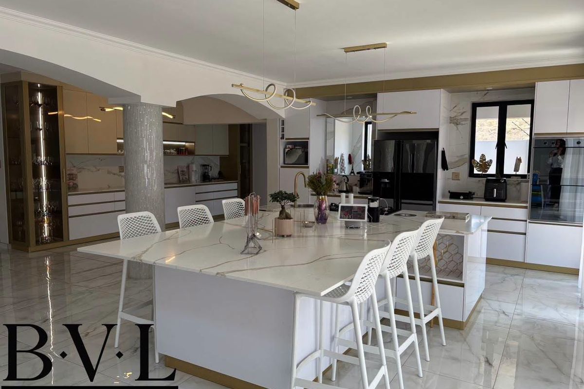 Modern, high-end kitchen featuring a large marble-topped island, integrated cabinetry, premium finishes, and elegant pendant lighting in an open-plan layout.