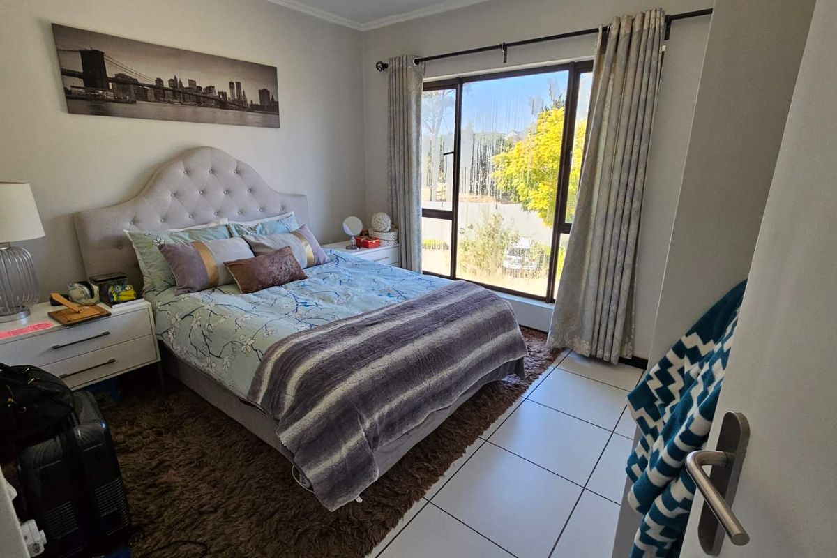 A well-lit bedroom featuring tiled flooring and a large sliding glass door that provides natural light and access to the exterior.