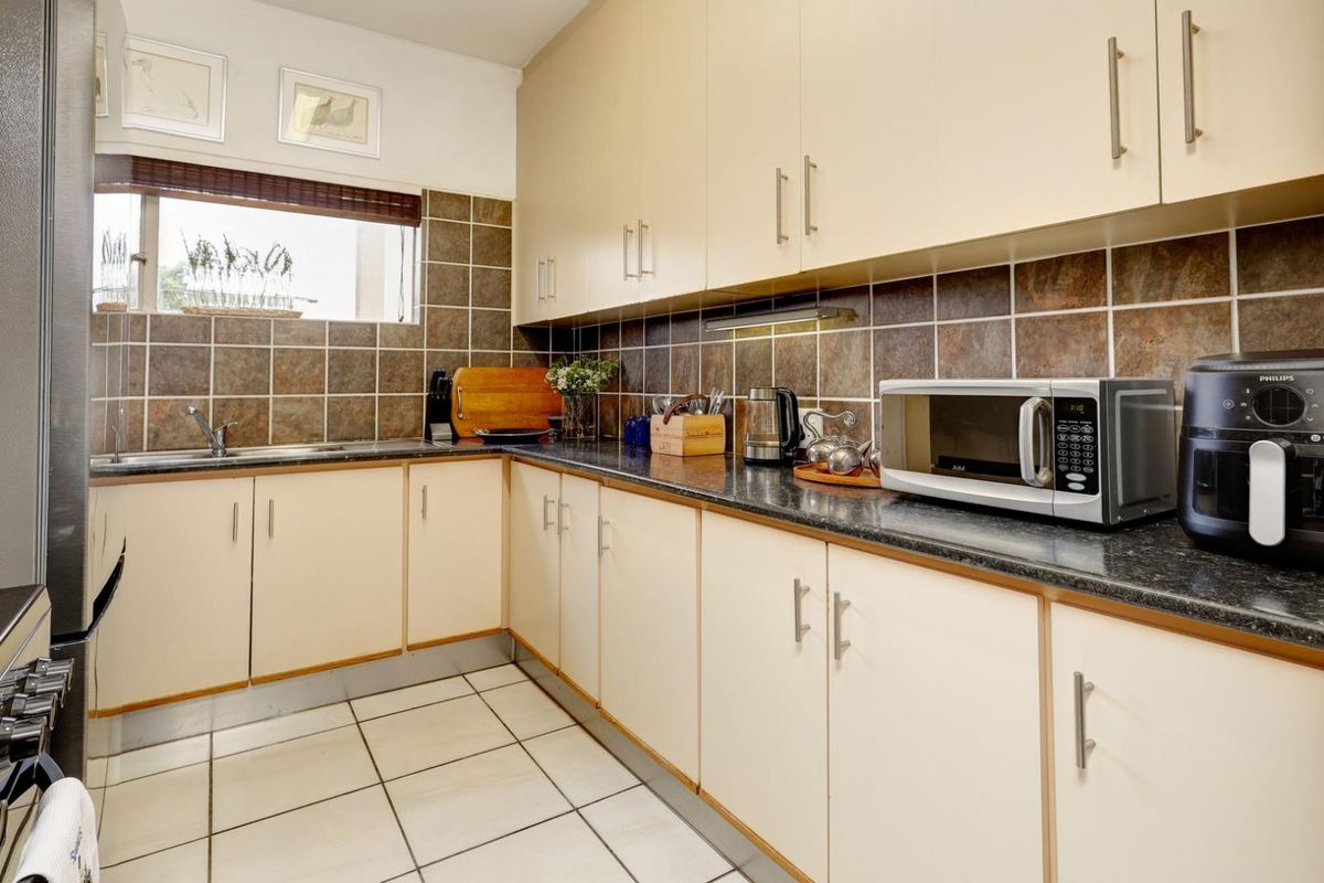 A functional kitchen featuring laminate cabinetry, granite countertops, tiled backsplash, and ceramic floor tiles, offering a practical layout for daily meal preparation.