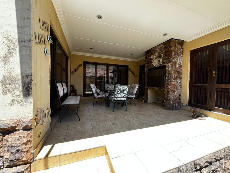 Covered patio area featuring a built-in braai with stone cladding, tiled flooring, and sliding door access to the interior living space.