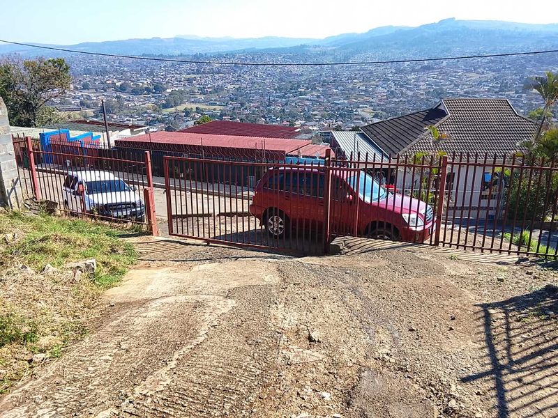 A view of the property entrance featuring a metal gate and a concrete driveway with an expansive outlook over the surrounding residential area.