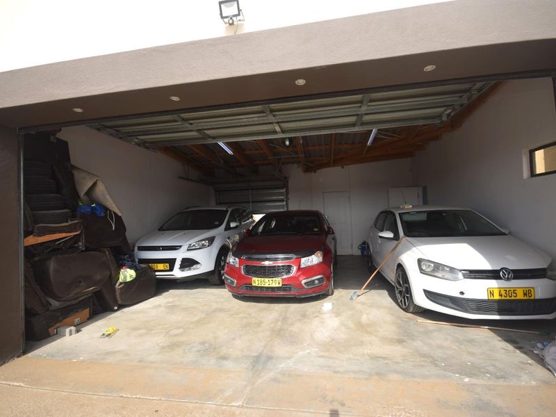 A spacious multi-vehicle garage featuring concrete flooring, exposed roof trusses, and recessed ceiling lighting.