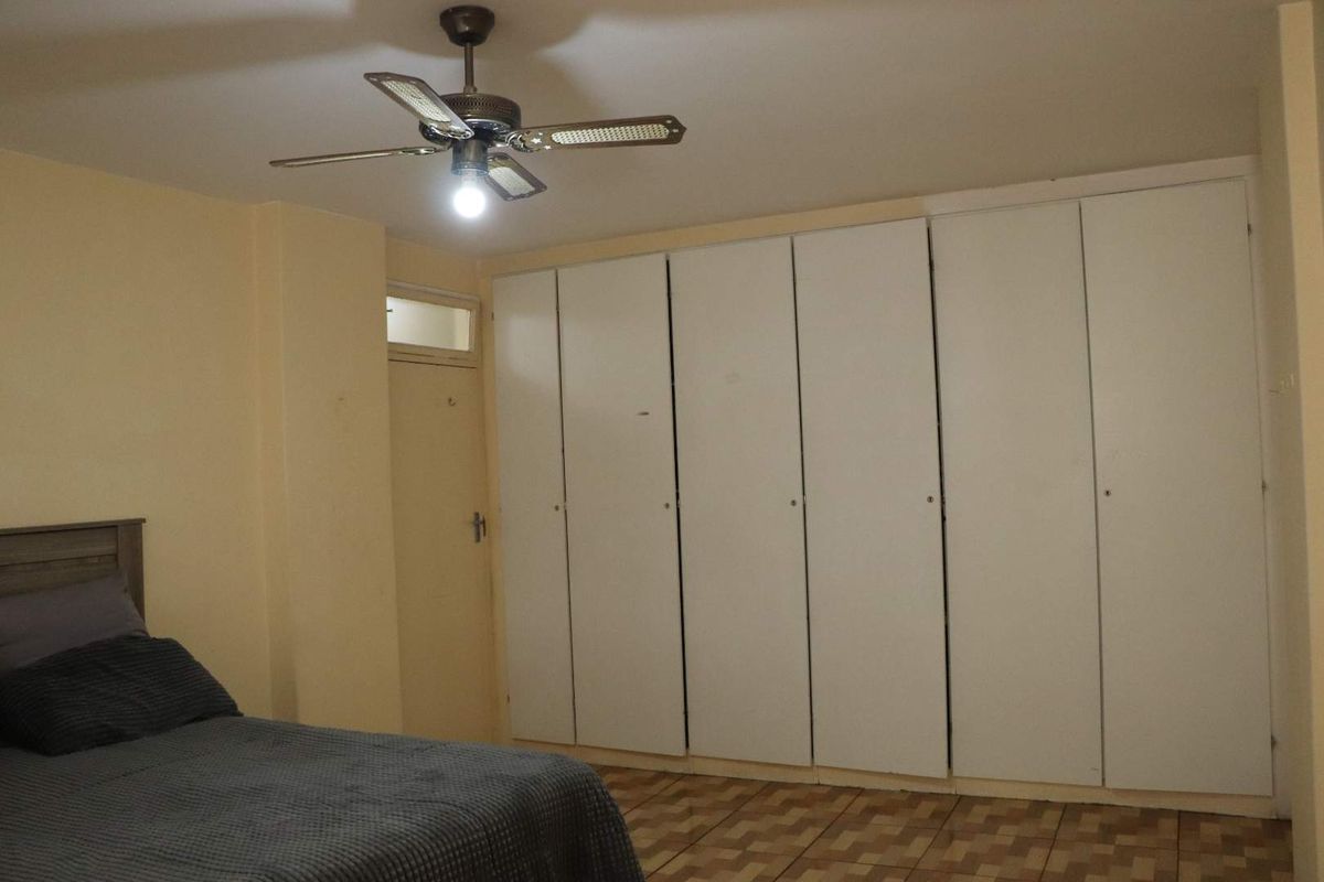Bedroom featuring a large wall-to-wall built-in wardrobe with white cabinetry, a ceiling fan, and tiled flooring.
