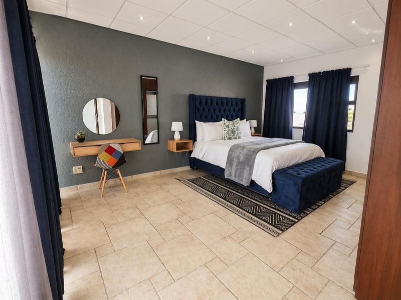 Spacious bedroom featuring tiled flooring, recessed ceiling lighting, and a neutral color palette with a dark accent wall.