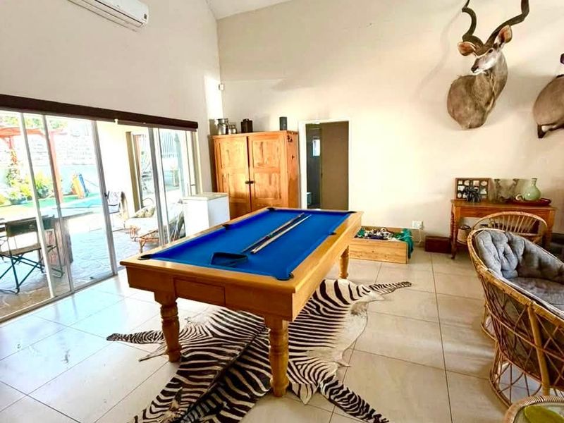 Spacious living area featuring high vaulted ceilings, large sliding glass doors providing outdoor access, and neutral tiled flooring throughout.