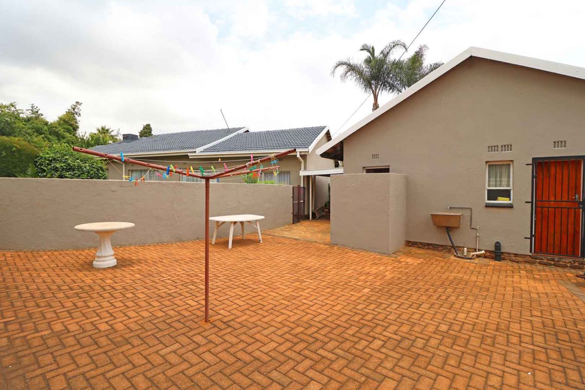 A paved rear courtyard area featuring a brick-paved surface, exterior wall, and a functional outdoor utility sink.