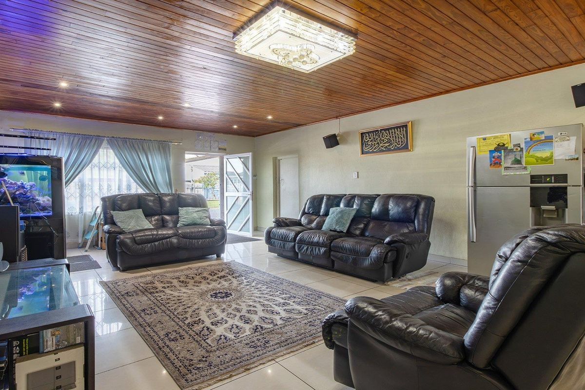 Spacious living room featuring a distinctive timber-clad ceiling, tiled flooring, and recessed lighting, providing a comfortable and functional family living space.