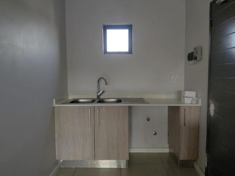 A functional laundry area featuring a double bowl sink, laminate cabinetry, and dedicated plumbing connections for appliances.