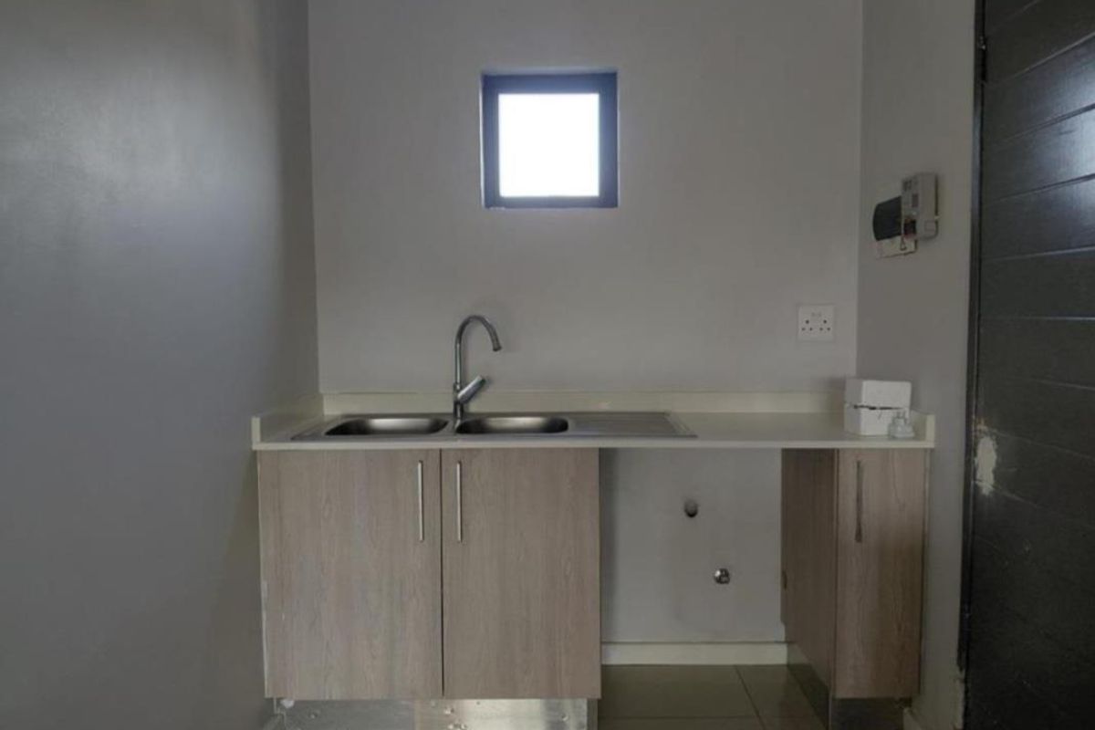 A functional laundry area featuring a double bowl sink, laminate cabinetry, and dedicated plumbing connections for appliances.
