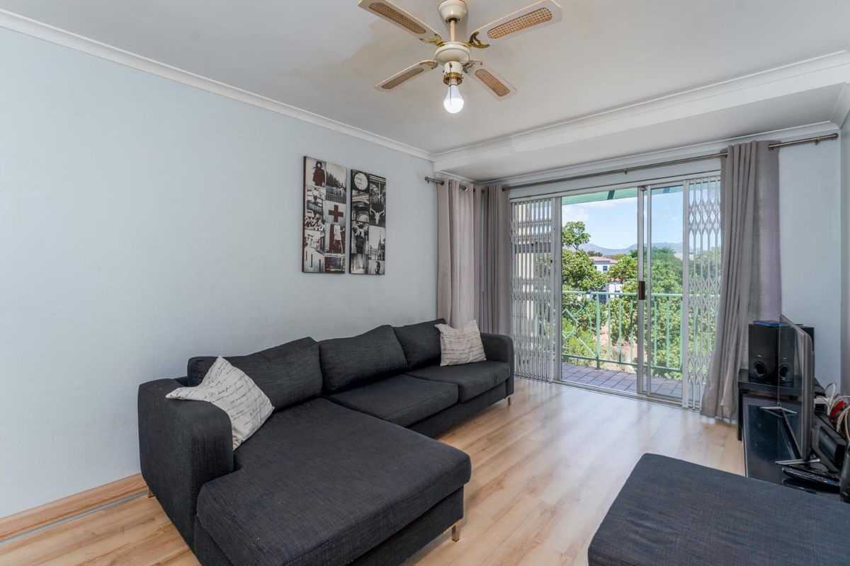 Living room featuring light wood-look flooring, a ceiling fan, and sliding glass doors opening onto a balcony with exterior views.