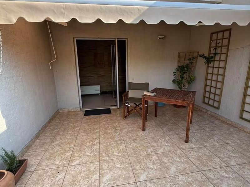 A covered outdoor patio area featuring tiled flooring and a retractable awning, providing a functional space for outdoor relaxation.