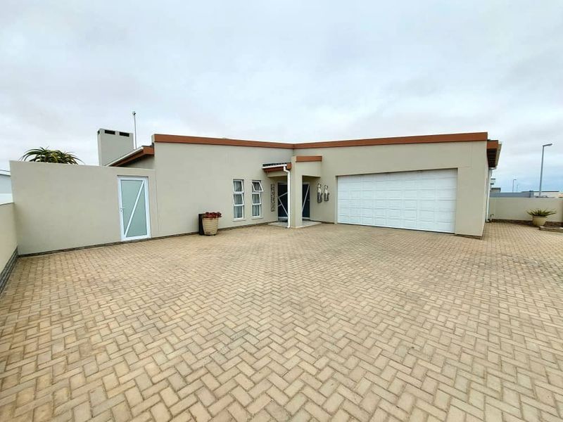Front exterior view of the house featuring a paved driveway, a double garage, and a modern facade with neutral tones.