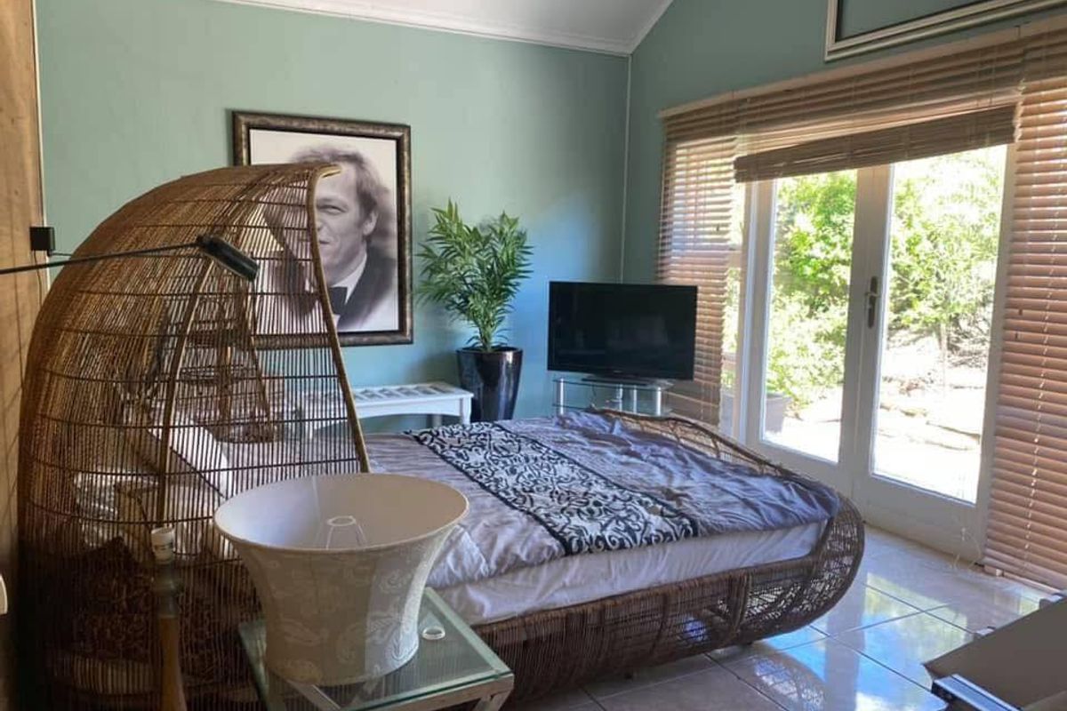 A bedroom featuring vaulted ceilings, tiled flooring, and large glass sliding doors providing direct access to the garden area.