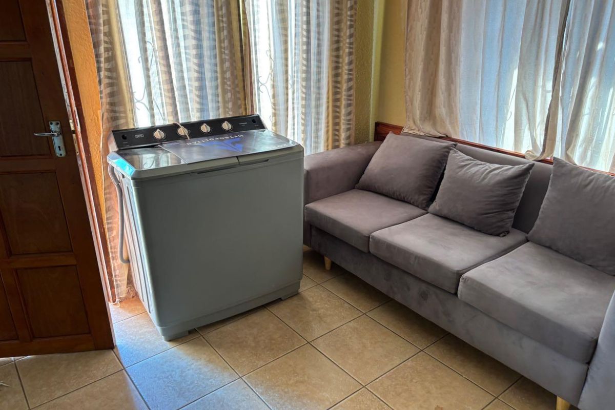 A functional room featuring tiled flooring and large windows with curtains, currently utilized as a multi-purpose space.