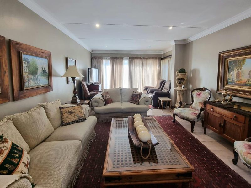 A spacious living room featuring tiled flooring, recessed downlighting, and decorative crown molding, offering a comfortable and well-defined seating area.