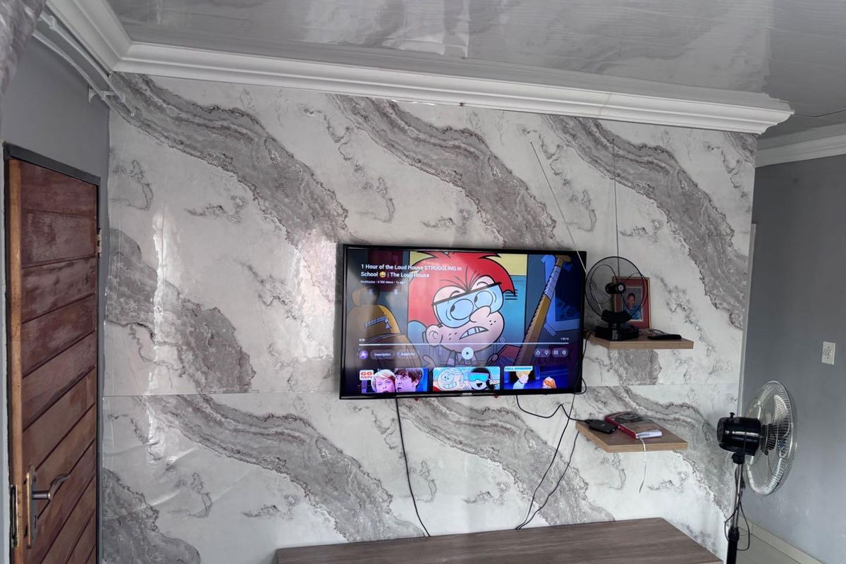Living room featuring a decorative marble-effect feature wall with a mounted television and floating shelving.