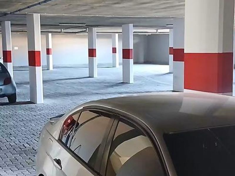 A spacious, covered parking garage featuring concrete structural columns and paved flooring.