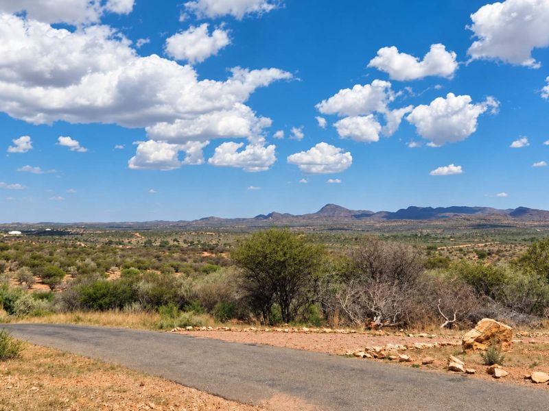 A scenic view of the expansive natural landscape and distant mountains, featuring a paved access road in the foreground.