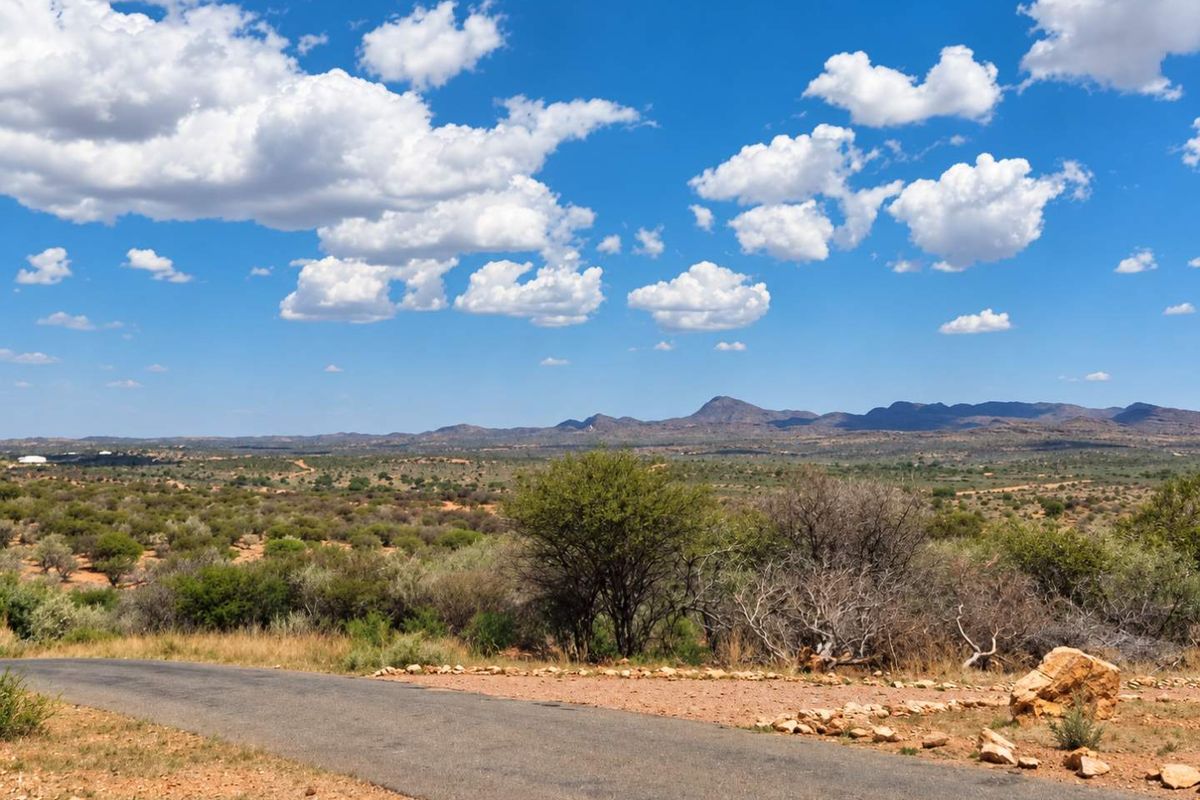 A scenic view of the expansive natural landscape and distant mountains, featuring a paved access road in the foreground.