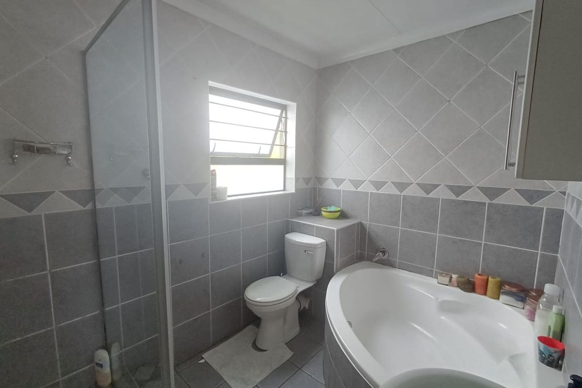 A functional bathroom featuring a corner bathtub, separate shower enclosure, and tiled finishes throughout.