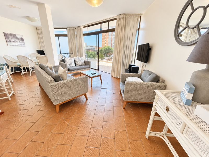 Spacious open-plan living area featuring ceramic tile flooring and large sliding glass doors leading to a private balcony with exterior views.
