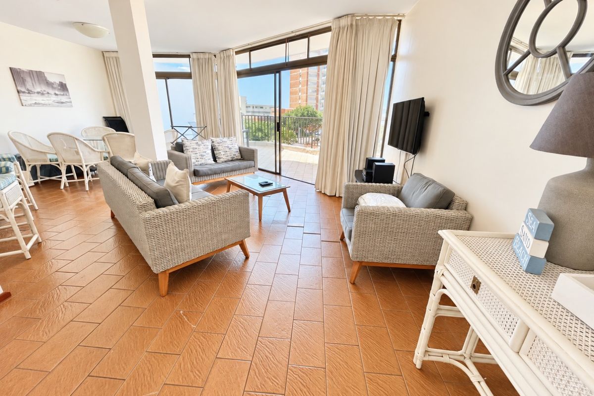 Spacious open-plan living area featuring ceramic tile flooring and large sliding glass doors leading to a private balcony with exterior views.