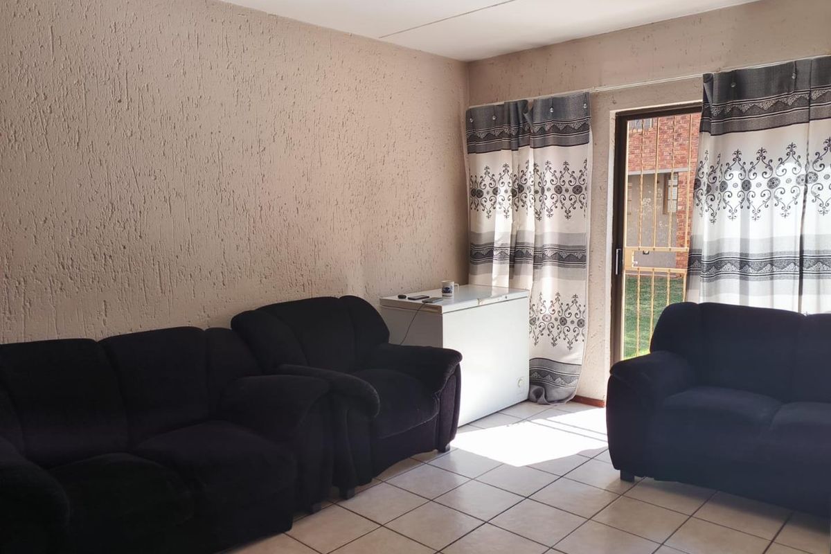 A living room featuring tiled flooring and a sliding glass door providing access to the exterior, with textured wall finishes.