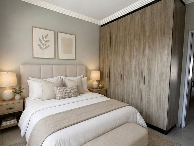 A well-maintained bedroom featuring neutral tones, crown molding, tiled flooring, and extensive built-in wooden cabinetry for storage.