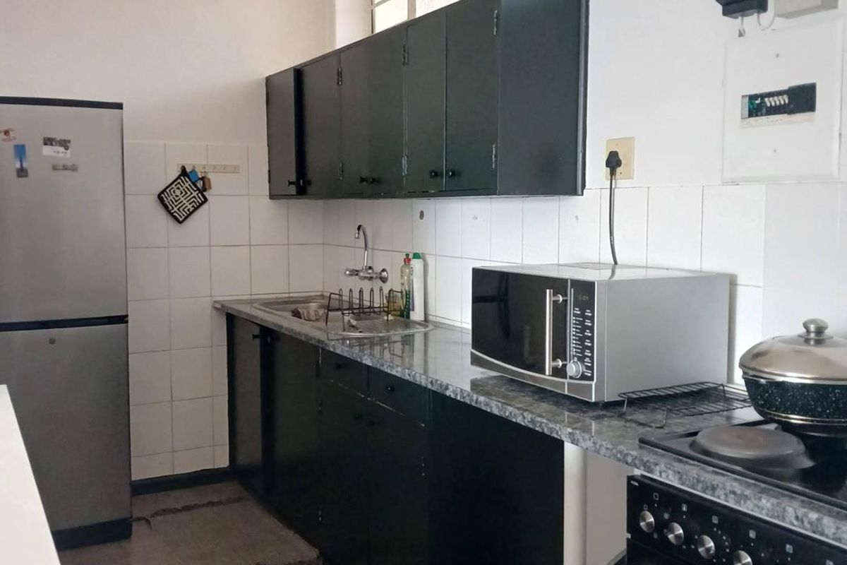 A functional kitchen featuring dark cabinetry, granite-look countertops, tiled splashbacks, and a built-in stove with an integrated hob.