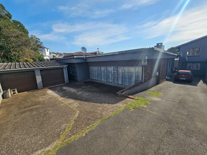 Front exterior view of the property featuring a double garage, concrete driveway, and brick facade with security system.