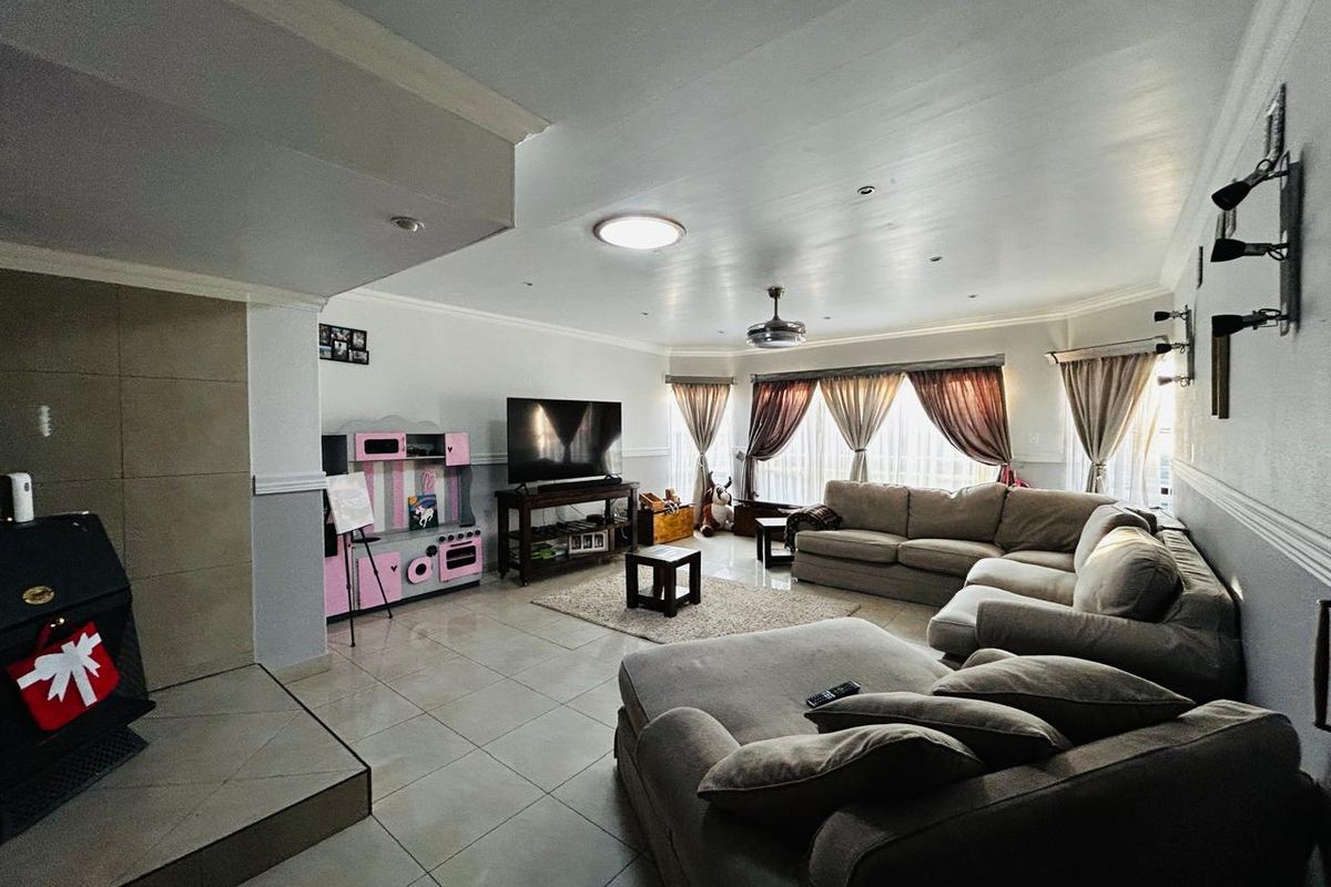 Spacious living room featuring tiled flooring, a built-in fireplace with tiled hearth, and large windows with curtains.